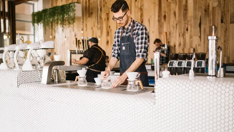 Carte de fidélité café : barista préparant des cafés au comptoir d'un coffee shop