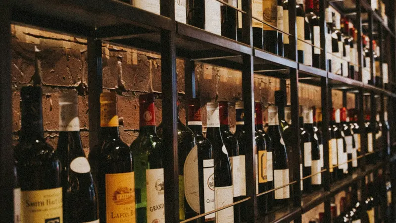 Carte de fidélité caviste : bouteilles de vin rangées sur les étagères d'une cave