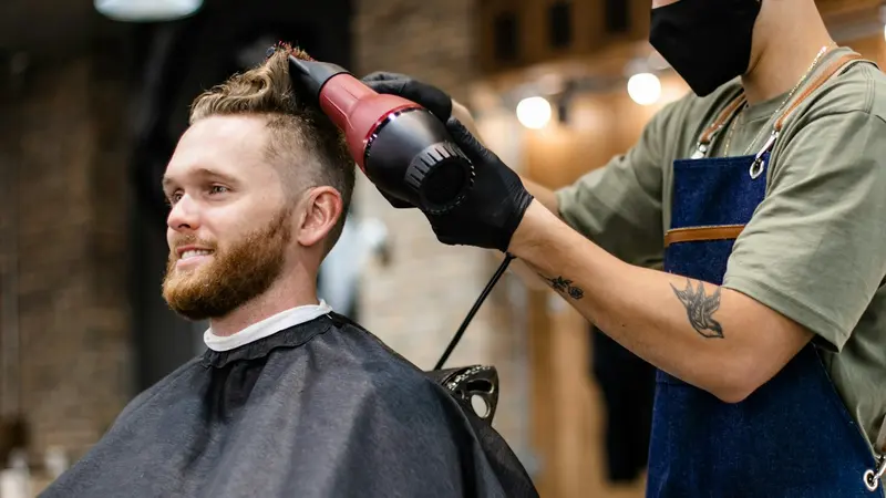 Carte de fidélité coiffeur : barbier séchant les cheveux d'un client dans son salon